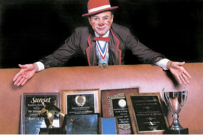 Gregory Popovich at a table of award plaques and trophies