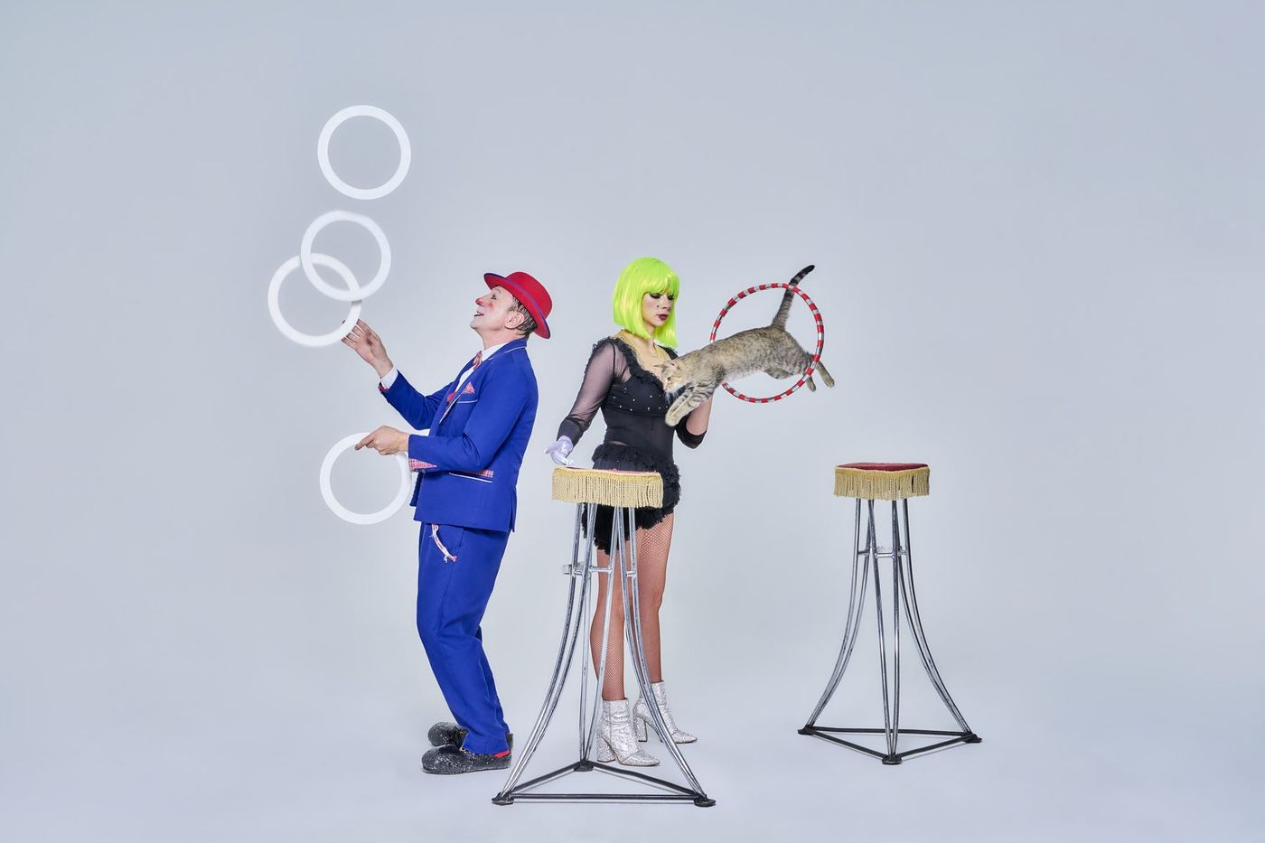Gregory Popovich juggling rings on stage while a rescued dog waits on its pedestal