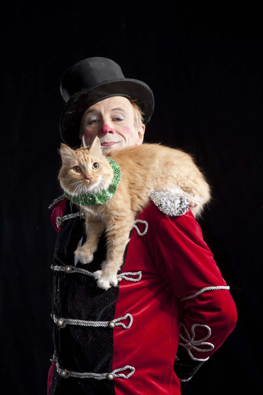 Gregory Popovich in a top hat and red ringmaster coat with a rescued cat on his shoulder